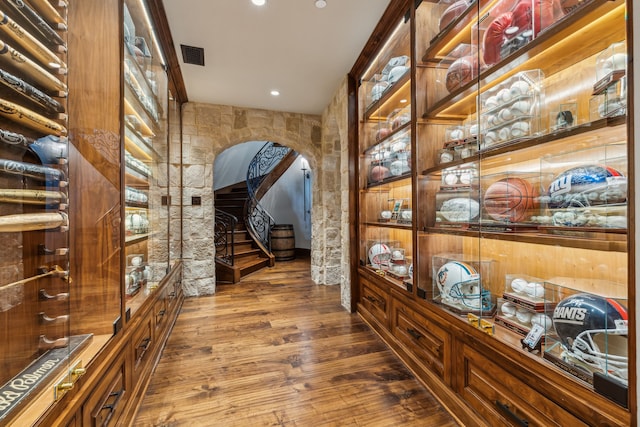 wine cellar featuring wood finished floors, arched walkways, and visible vents