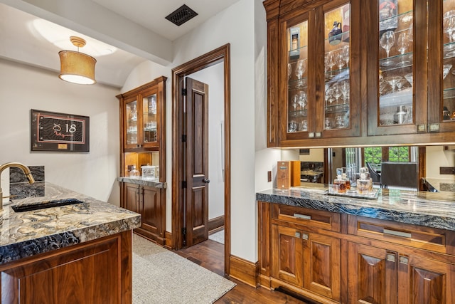 bar featuring pendant lighting, a sink, wet bar, baseboards, and dark wood-style flooring