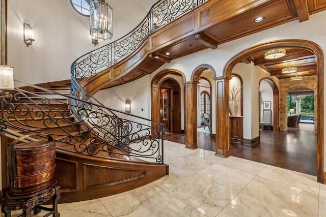 staircase with beam ceiling, arched walkways, decorative columns, baseboards, and wood ceiling