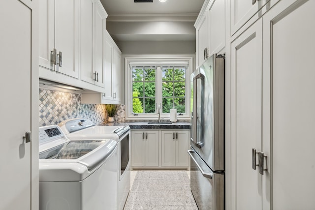 laundry room with visible vents, crown molding, washing machine and dryer, cabinet space, and a sink