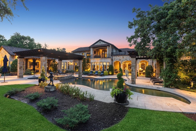 rear view of property with stone siding, a balcony, and a patio