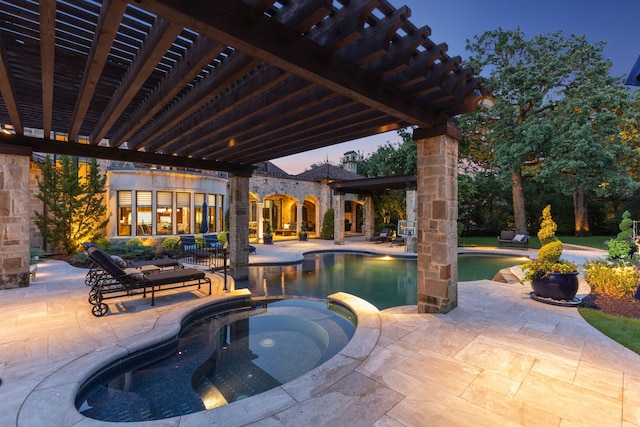 pool at dusk featuring a patio area, a pool with connected hot tub, and a pergola