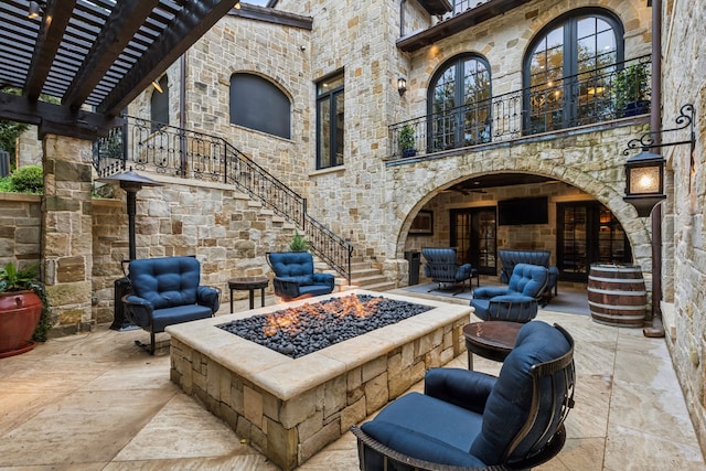 view of patio with a fire pit, a balcony, and stairs