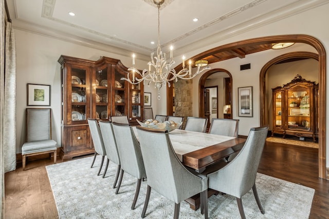 dining space with a chandelier, arched walkways, a raised ceiling, and wood finished floors