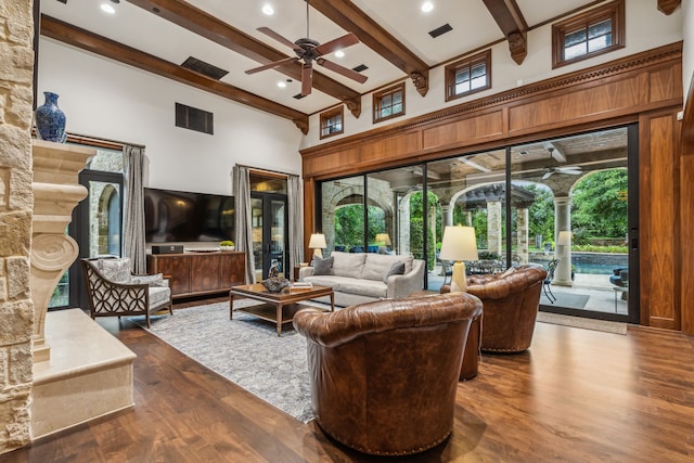 living area featuring dark wood-style floors, visible vents, ceiling fan, a towering ceiling, and beamed ceiling