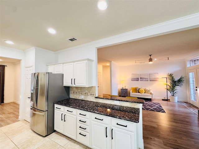 kitchen with visible vents, a peninsula, stainless steel refrigerator with ice dispenser, crown molding, and open floor plan