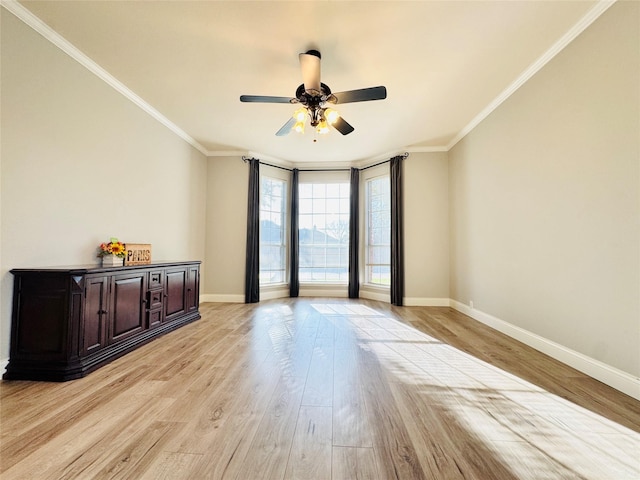 spare room with light wood-style flooring, crown molding, baseboards, and ceiling fan