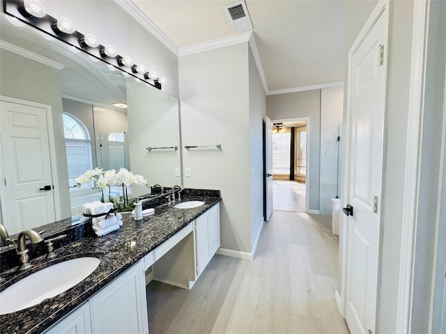 bathroom featuring visible vents, ornamental molding, wood finished floors, and a sink