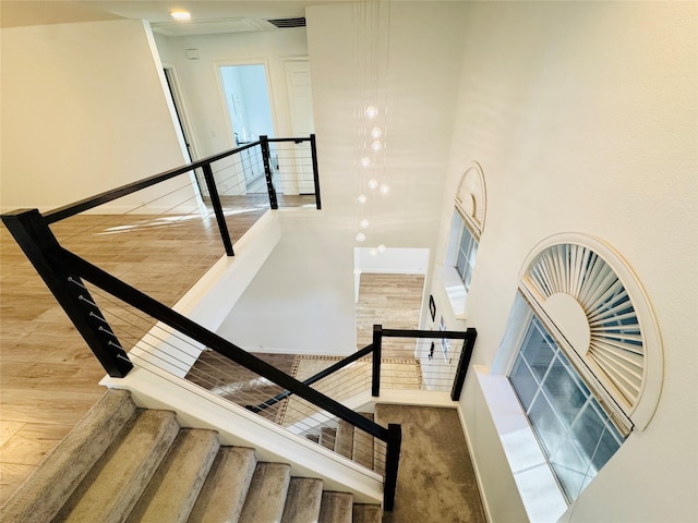 stairs featuring visible vents, a high ceiling, baseboards, and wood finished floors