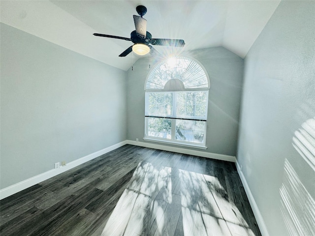 unfurnished room featuring vaulted ceiling, dark wood-style floors, baseboards, and ceiling fan