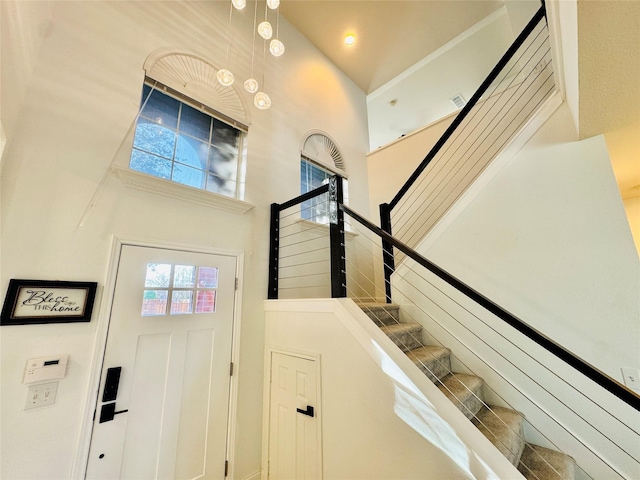 foyer entrance featuring stairway, a high ceiling, and visible vents