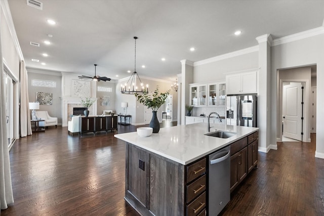 kitchen featuring light countertops, appliances with stainless steel finishes, a fireplace, white cabinetry, and a sink