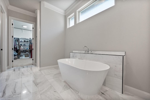 full bath with a freestanding tub, a walk in closet, marble finish floor, and ornamental molding