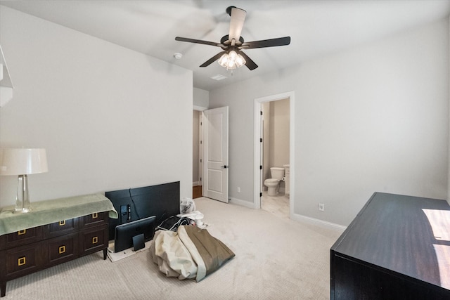 bedroom with ensuite bath, light colored carpet, baseboards, and ceiling fan