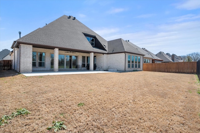 rear view of house with a patio, brick siding, a shingled roof, and fence