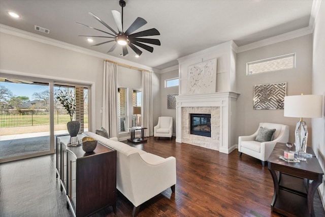 living room with visible vents, wood finished floors, a fireplace, crown molding, and ceiling fan