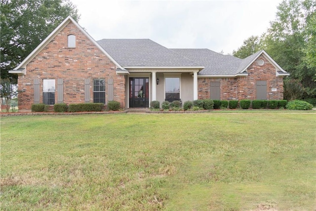 view of front of house featuring brick siding, a front lawn, and a shingled roof