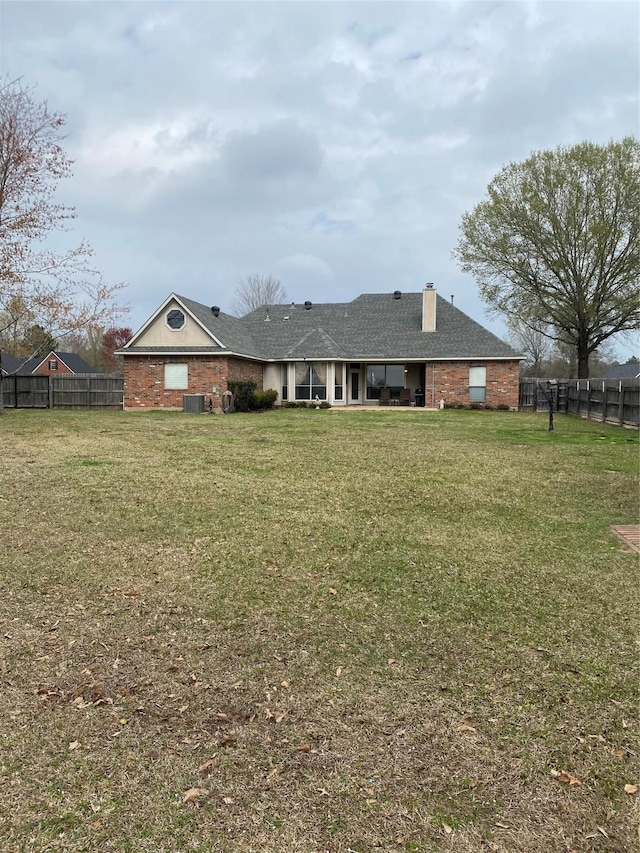 rear view of house with a lawn, fence, and a chimney