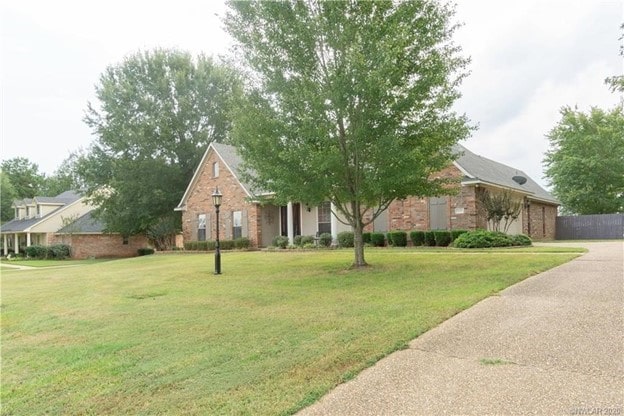 view of front of house with brick siding, an attached garage, concrete driveway, and a front yard