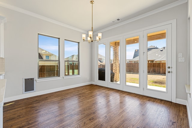 unfurnished dining area featuring visible vents, baseboards, ornamental molding, wood finished floors, and a notable chandelier