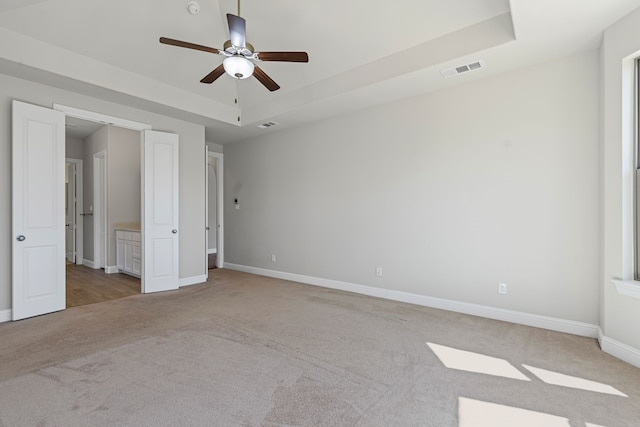 unfurnished bedroom featuring a ceiling fan, baseboards, visible vents, carpet floors, and a raised ceiling