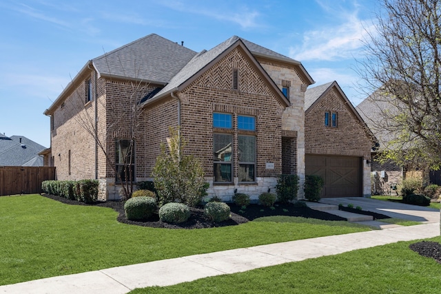 french country inspired facade with driveway, fence, a front yard, a garage, and brick siding