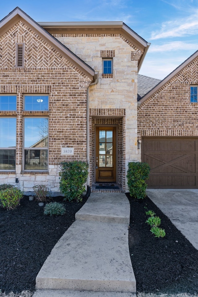 doorway to property with brick siding, stone siding, concrete driveway, and a garage