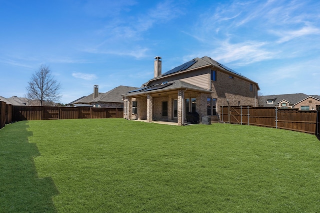 back of property featuring a yard, a fenced backyard, and brick siding