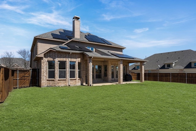 back of property featuring a yard, a patio, brick siding, and a fenced backyard