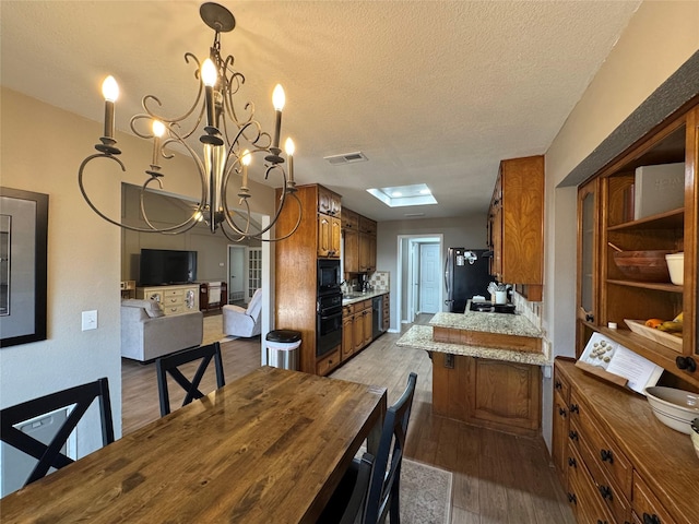 dining area with wood finished floors, visible vents, a chandelier, and a textured ceiling