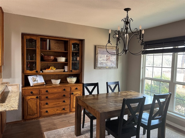 dining space with dark wood-style floors, a notable chandelier, and baseboards