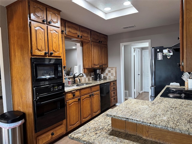 kitchen featuring a sink, visible vents, black appliances, and brown cabinetry