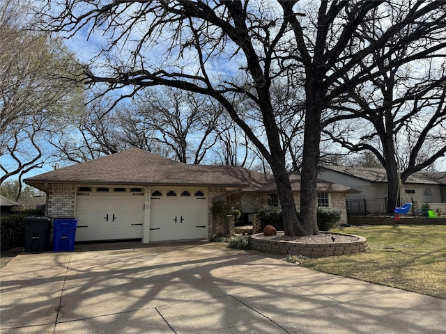 single story home with brick siding, concrete driveway, a front lawn, and a shingled roof