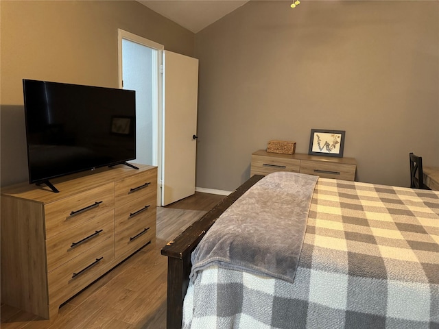 bedroom featuring dark wood finished floors, vaulted ceiling, and baseboards