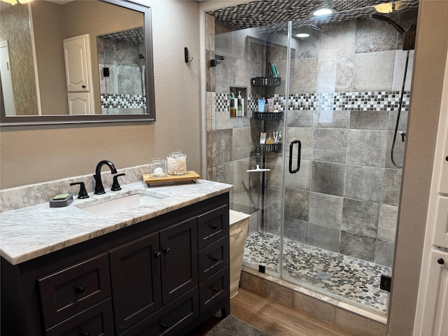 full bathroom with vanity, a shower stall, and wood finished floors