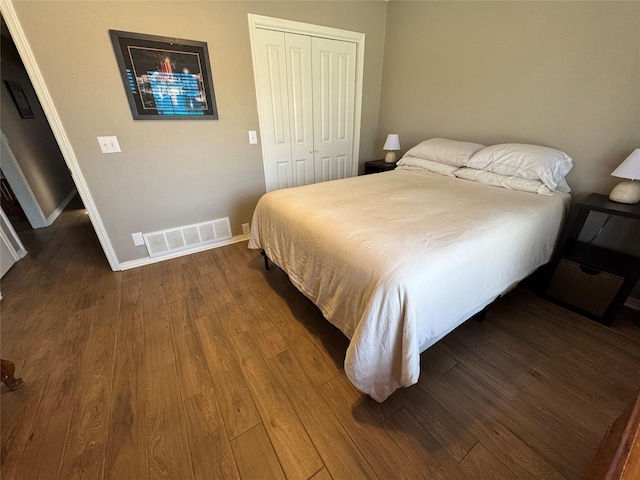 bedroom with visible vents, baseboards, dark wood-type flooring, and a closet