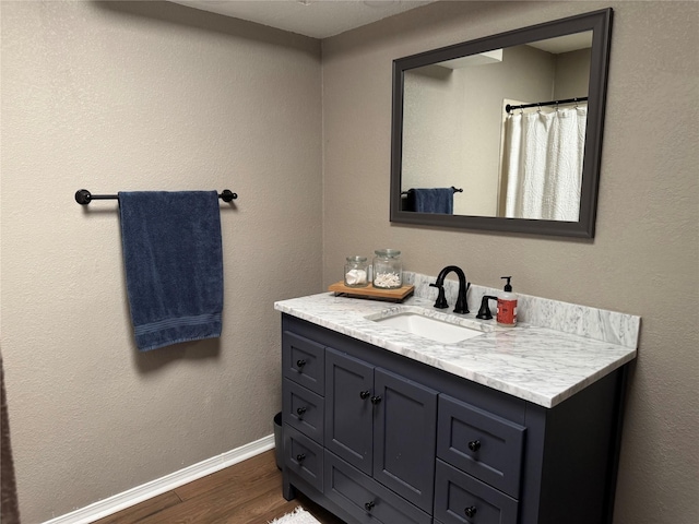 full bathroom with vanity, baseboards, and wood finished floors