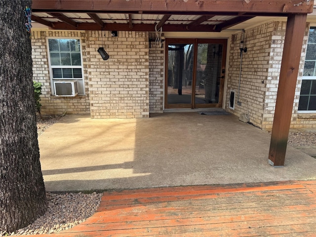 doorway to property with a patio, cooling unit, and brick siding