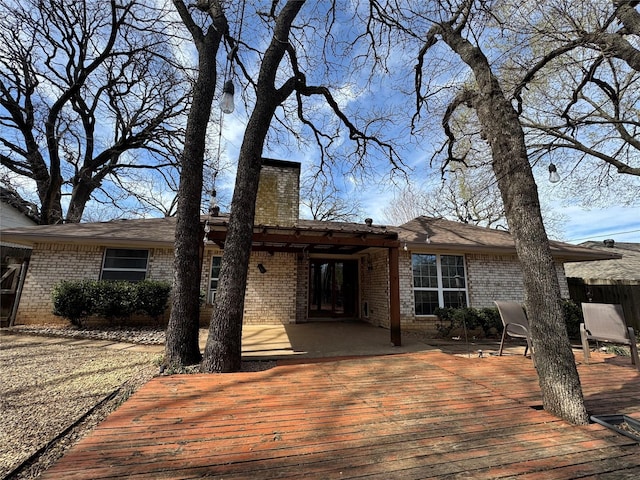 exterior space with brick siding, a chimney, and a wooden deck