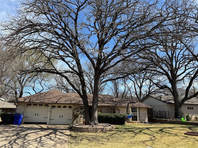 view of front facade featuring fence, brick siding, a garage, and driveway