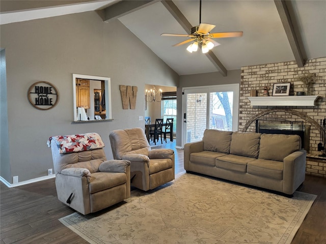 living area with baseboards, beam ceiling, ceiling fan with notable chandelier, a fireplace, and wood finished floors