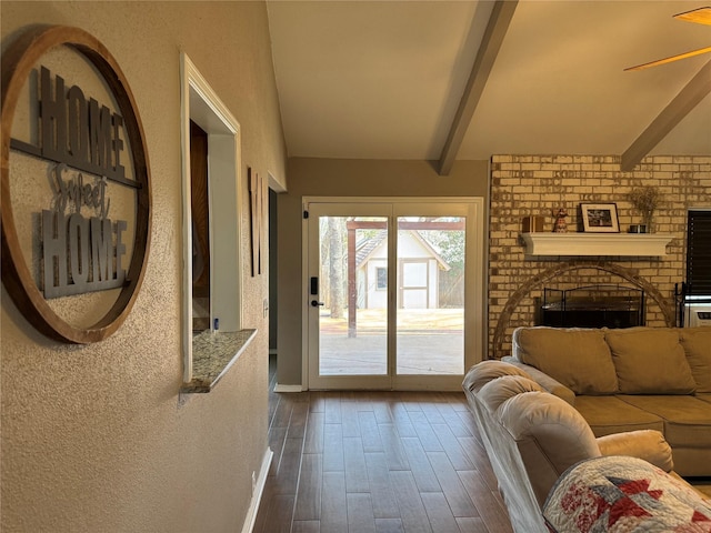 interior space featuring beamed ceiling, dark wood-type flooring, ceiling fan, and a fireplace