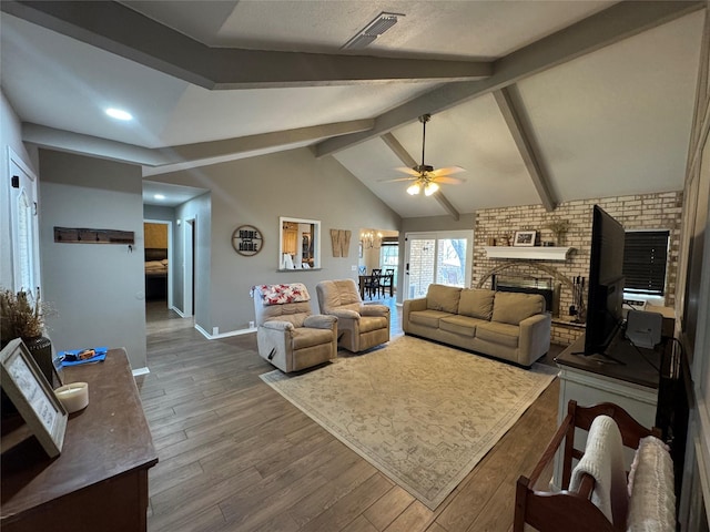 living area featuring a ceiling fan, baseboards, lofted ceiling with beams, dark wood-type flooring, and a brick fireplace