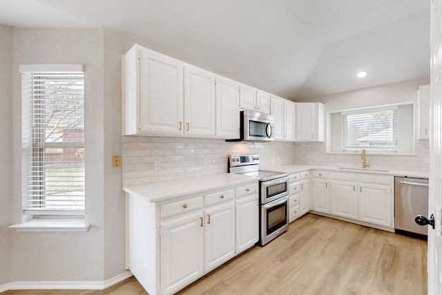 kitchen with decorative backsplash, stainless steel appliances, lofted ceiling, and a sink