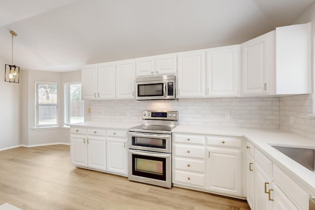 kitchen with decorative backsplash, light countertops, light wood finished floors, and appliances with stainless steel finishes