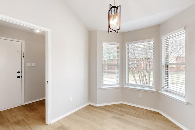 unfurnished dining area featuring light wood-type flooring, baseboards, and a chandelier