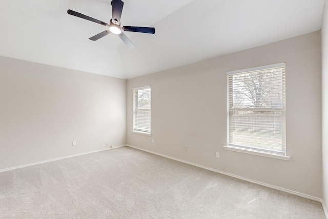 spare room featuring light carpet, baseboards, a ceiling fan, and vaulted ceiling