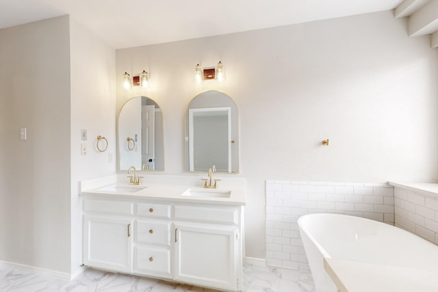 bathroom featuring a freestanding bath, double vanity, marble finish floor, and a sink