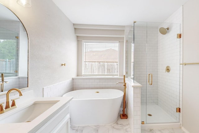 full bathroom with vanity, a freestanding bath, a shower stall, tile walls, and marble finish floor