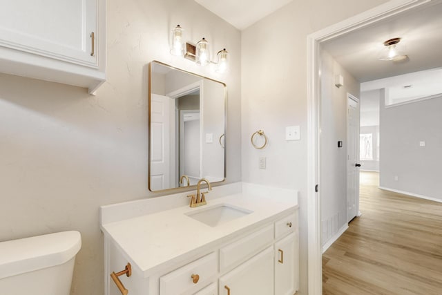 bathroom featuring toilet, vanity, baseboards, and wood finished floors